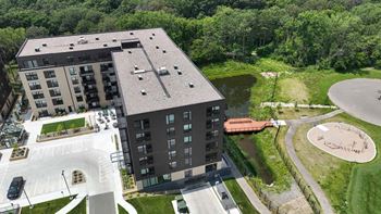an aerial view of an apartment building with a parking lot and a pond